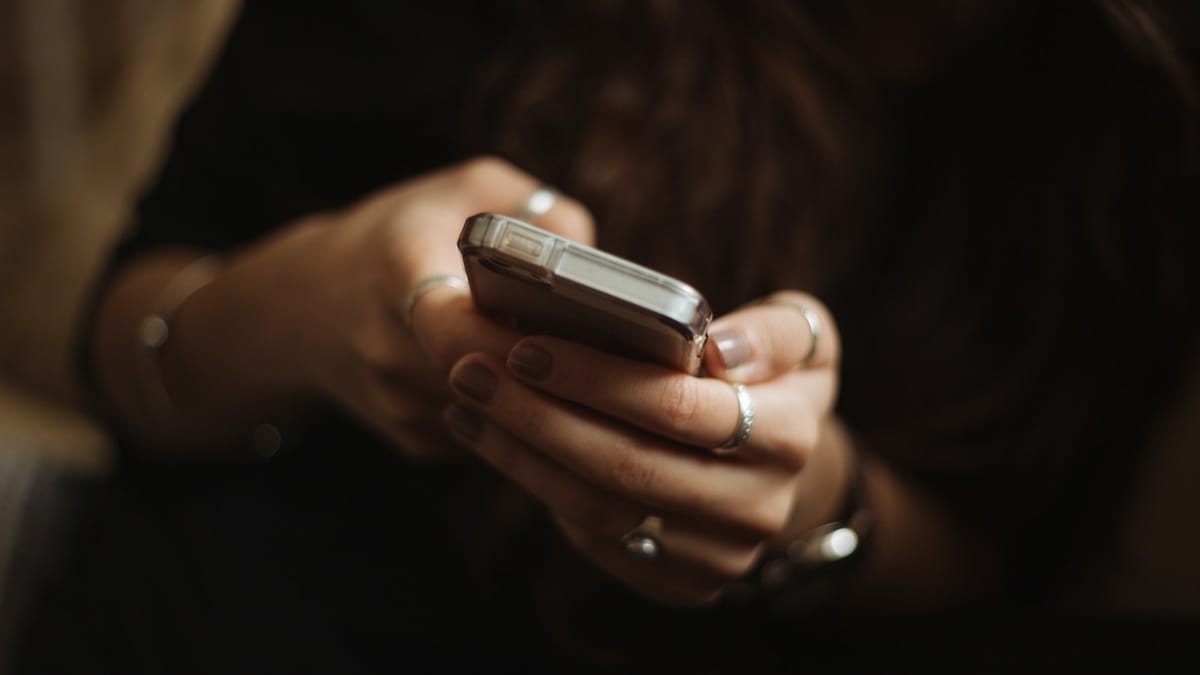 Close-up of hands holding a smartphone in low light